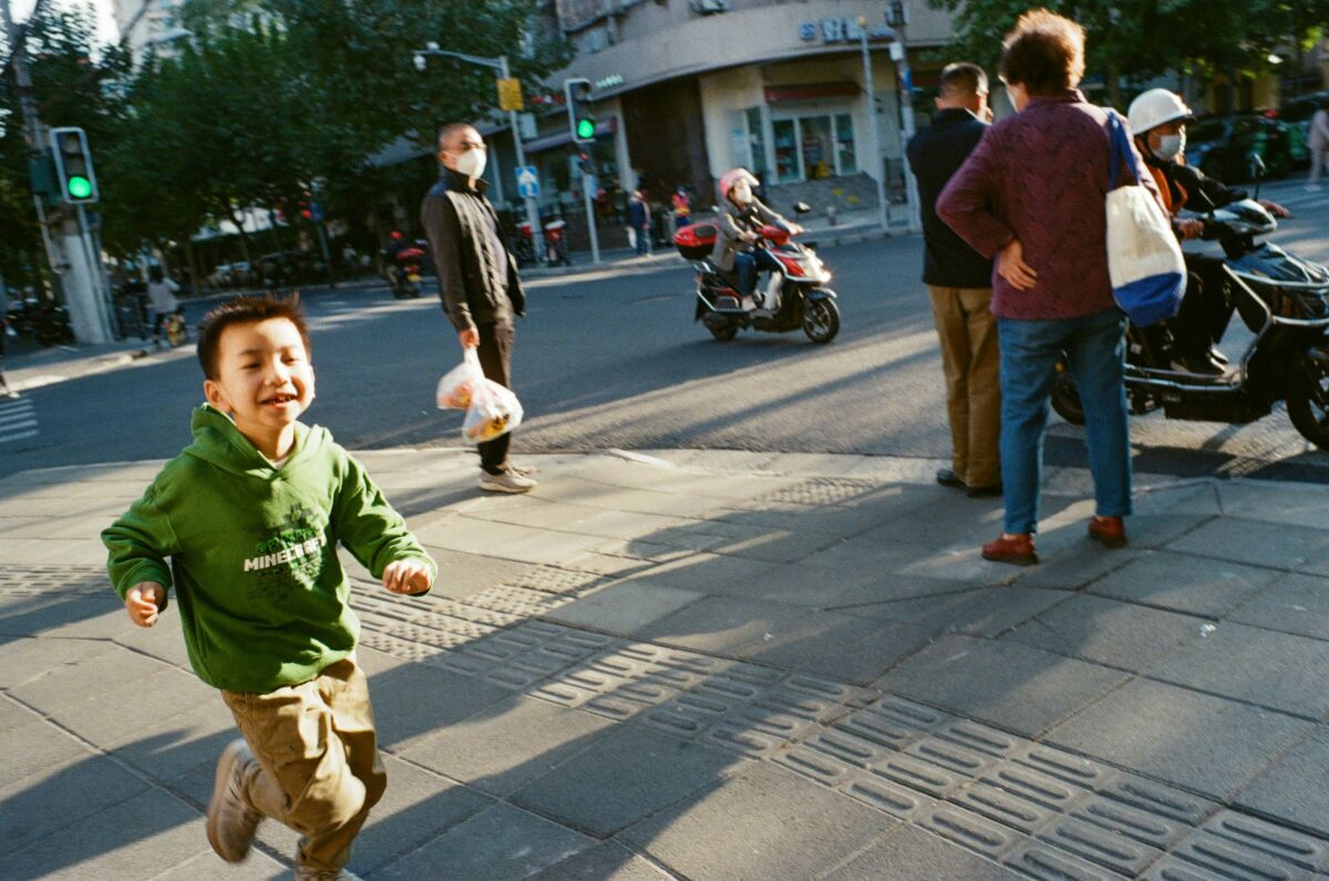 A joyful child runs across a city street.