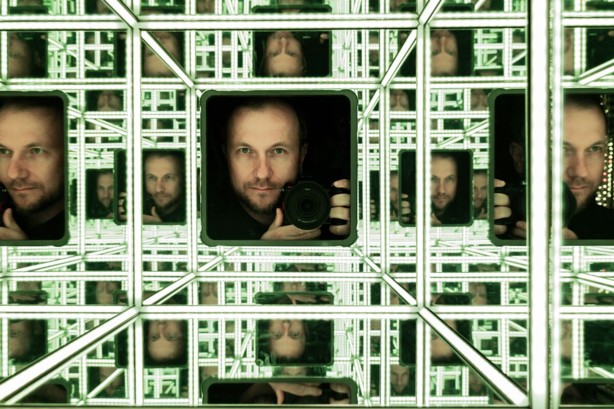 Man takes a selfie in a mirrored infinity room.