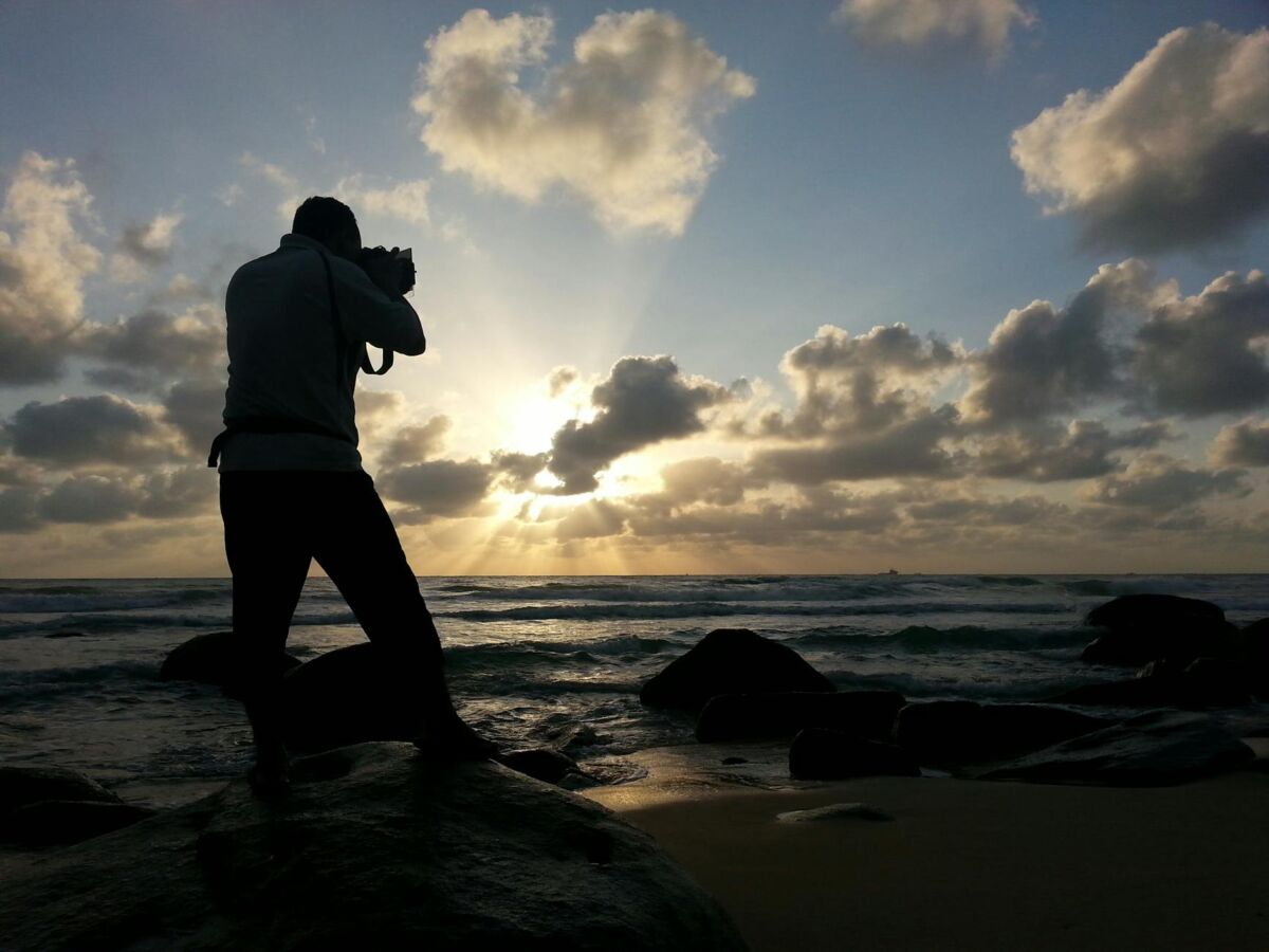person capturing photo near sea under clear blue and white cloudy sky during daytime